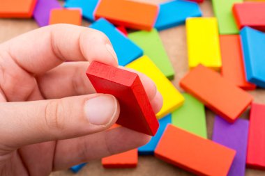 Çeşitli renklerin ahşap bloklarından birini tutarken