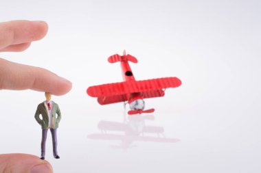 Beyaz bir arka plan üzerinde kırmızı bir insan figürü uçakla tutan el