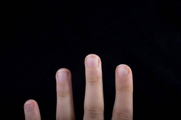 Four fingers of a child hand partly seen in black background