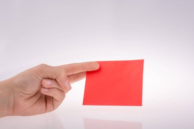 Beyaz arkaplan üzerine kırmızı bir kağıt tutuyordu.