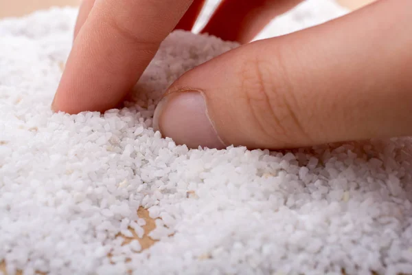 Mano Tocando Pequeñas Piedras Blancas Esparcidas Sobre Fondo Madera —  Fotos de Stock