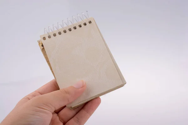 Χέρι Κρατώντας Ένα Σημειωματάριο Σπιράλ Λευκό Φόντο — Φωτογραφία Αρχείου