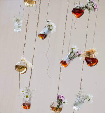 İplere asılı çiçekli bitkisel çay şişeleri