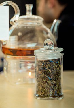 Cam çaydanlıkta demlenmiş bitki çayı ve şişede çay bitkisi.