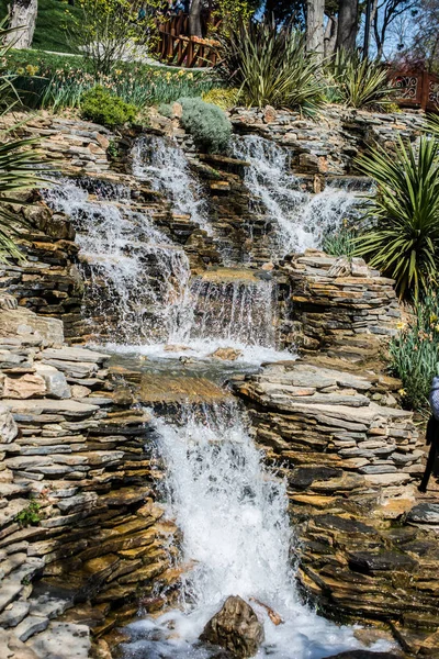 Küçük bir göle dökülen kayalık bir şelale.