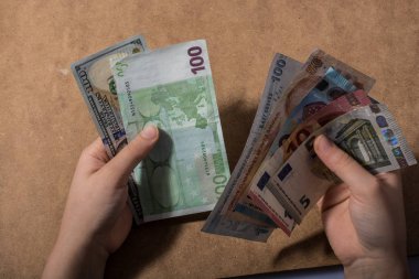 El ele tutuşan Amerikan doları banknotları ahşap arka planda izole edilmiş.