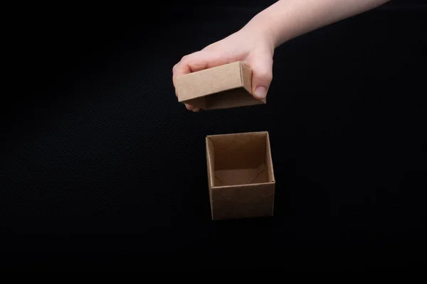 Caixa de papelão de abertura de mão em um fundo preto — Fotografia de Stock