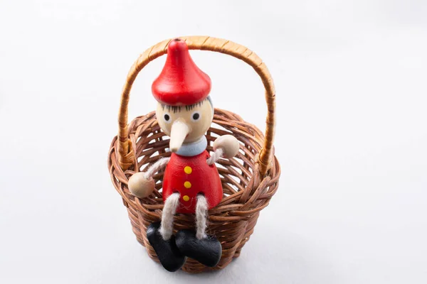 Figura de juguete Pinochio sentado en una cesta — Foto de Stock