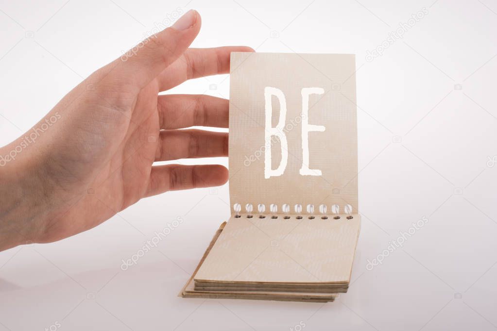 Hand holding a notebook with wording be