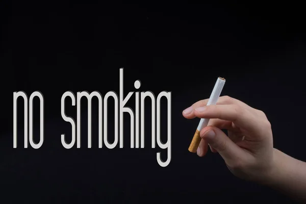 Hand hält eine Zigarette auf schwarzem Hintergrund — Stockfoto