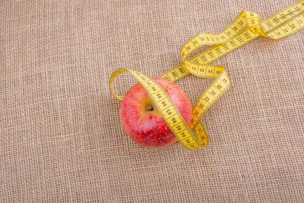 Red apple with a measurement  tape on it — Stock Photo, Image