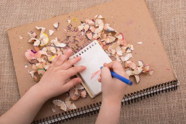 Spiral defter üzerinde bir renk kalem tutan el 