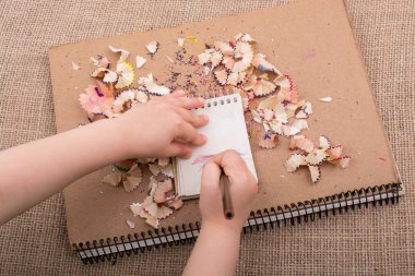 Spiral defter üzerinde bir renk kalem tutan el 