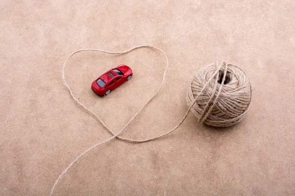 Rode speelgoed auto en een spoel van de draad vormen een hart vorm — Stockfoto