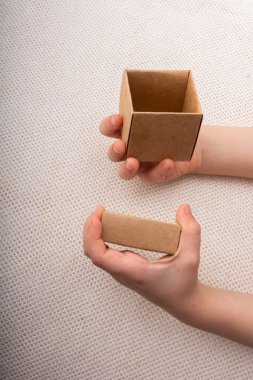 Beyaz bir arkaplanda el ele tutuşan karton kutu 