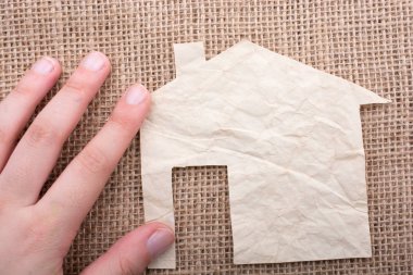 Tuval üzerinde bir kağıt ev tutan el 