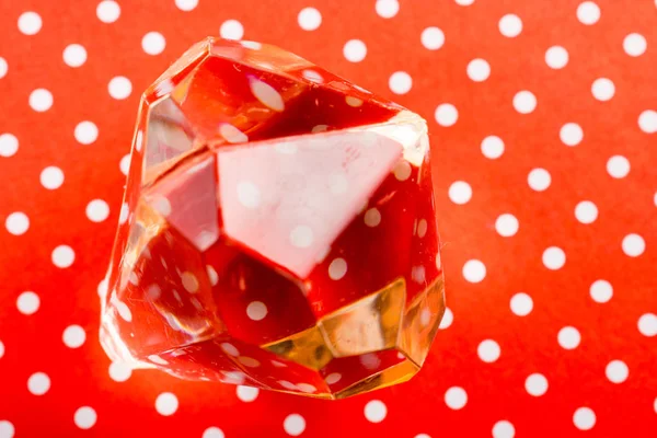 Um diamante transparente em um fundo texturizado vermelho — Fotografia de Stock