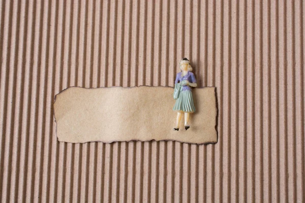 Woman figurine on piece of burnt  paper — Stock Photo, Image