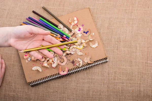 Hand hält Farbstift über ein Notizbuch — Stockfoto