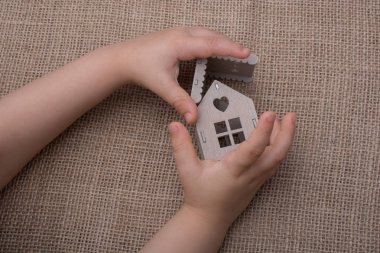 Bir tuval üzerine bir model ev tutan çocuk