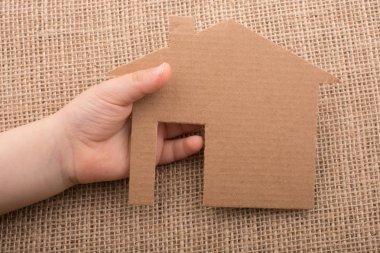 Tuval üzerinde bir kağıt ev tutan el 