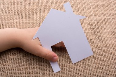 Tuval üzerinde bir kağıt ev tutan el 