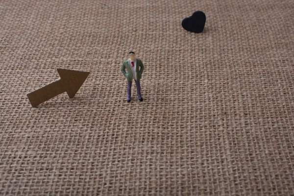 Figurina e freccia tagliate di carta marrone accanto a un cuore — Foto Stock