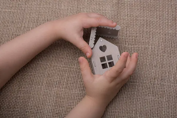 Bir tuval üzerine bir model ev tutan çocuk