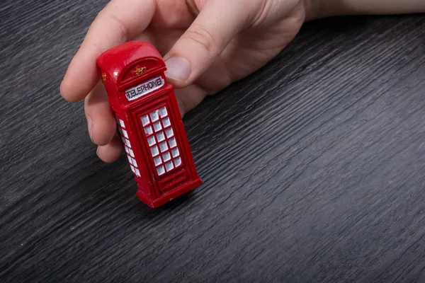 Mano sosteniendo una cabina telefónica roja — Foto de Stock