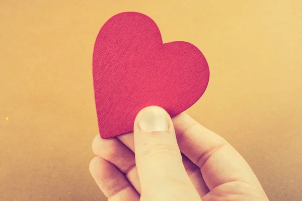 Color rojo objeto en forma de corazón en la mano —  Fotos de Stock