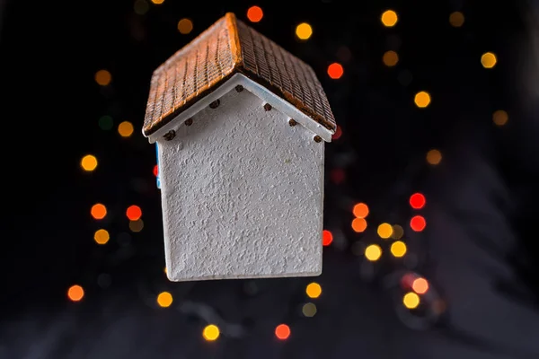 Little model house on bokeh lights on dark background