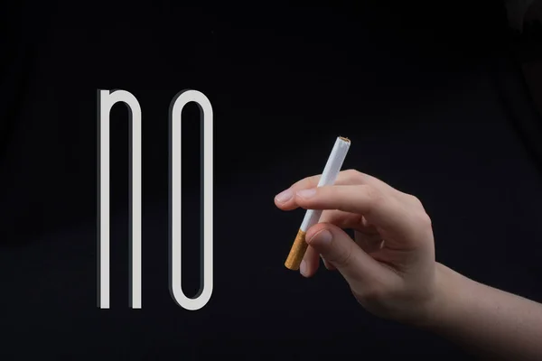 Ruka drží cigaretu na černém pozadí — Stock fotografie