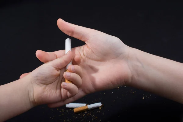 Hand är att ge ut cigarett på svart bakgrund — Stockfoto