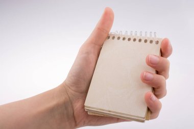 Beyaz arkaplanda elle tutulan spiral defter