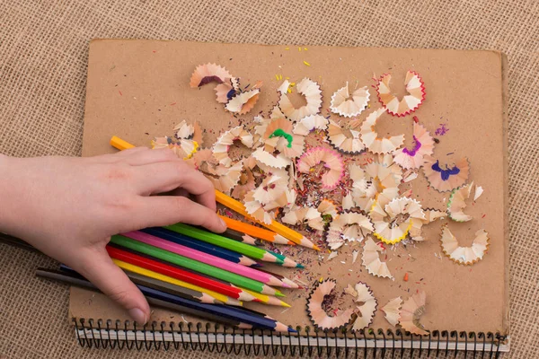 Hand holding Color Pencils over a notebook — Stock Photo, Image