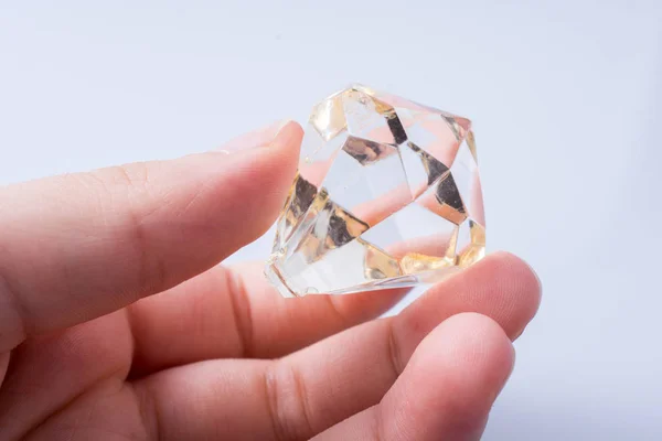 Χέρι κρατώντας ένα διαφανές διαμάντι σε λευκό φόντο — Φωτογραφία Αρχείου