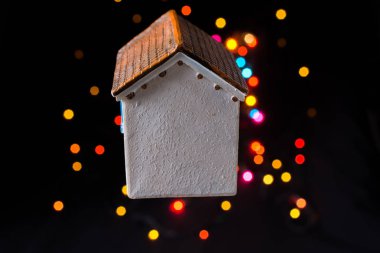 Koyu arkaplanda Bokeh ışıkları olan küçük model ev.