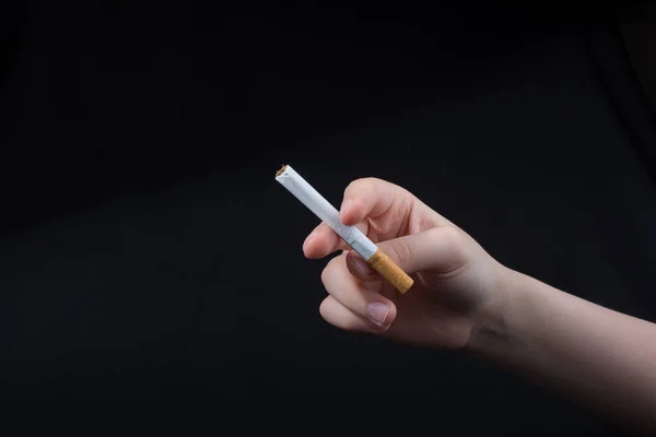 Hand håller en cigarett på svart bakgrund — Stockfoto
