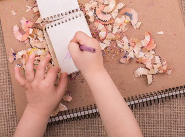 Spiral defter üzerinde bir renk kalem tutan el 