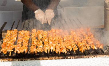 Adam dışarıda barbekü yapıyor.