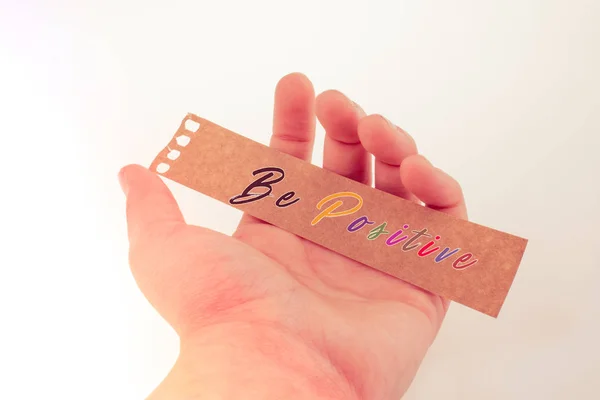 Be positive quote lettering on torn notepaper in hand