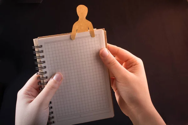 Man shape cut out of paper in notebbok