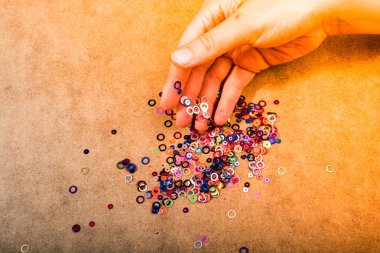 Ahşap arka plan müziği üzerinde dekoratif parlak renkli konfeti tutan el