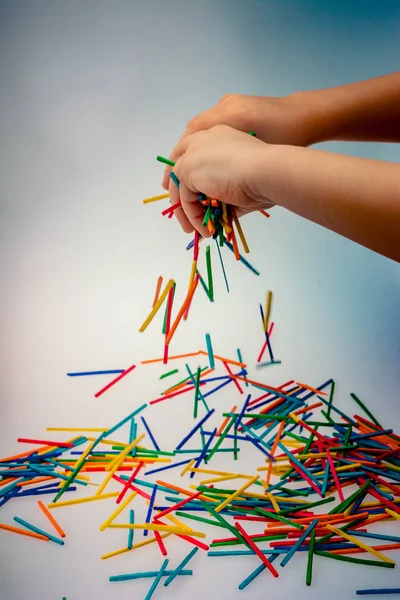 Hand letting coloured wooden  sticks drop on white — Stock Photo, Image