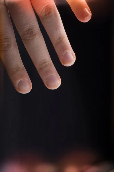 Four fingers of a human hand partly seen in view