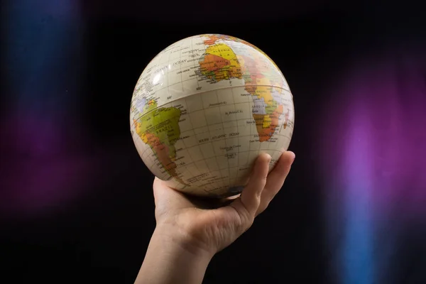 Hand holding a globe  with the map on it