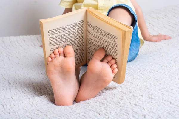 Menino segurando livro em pés como conceito Dia Mundial do Livro — Fotografia de Stock