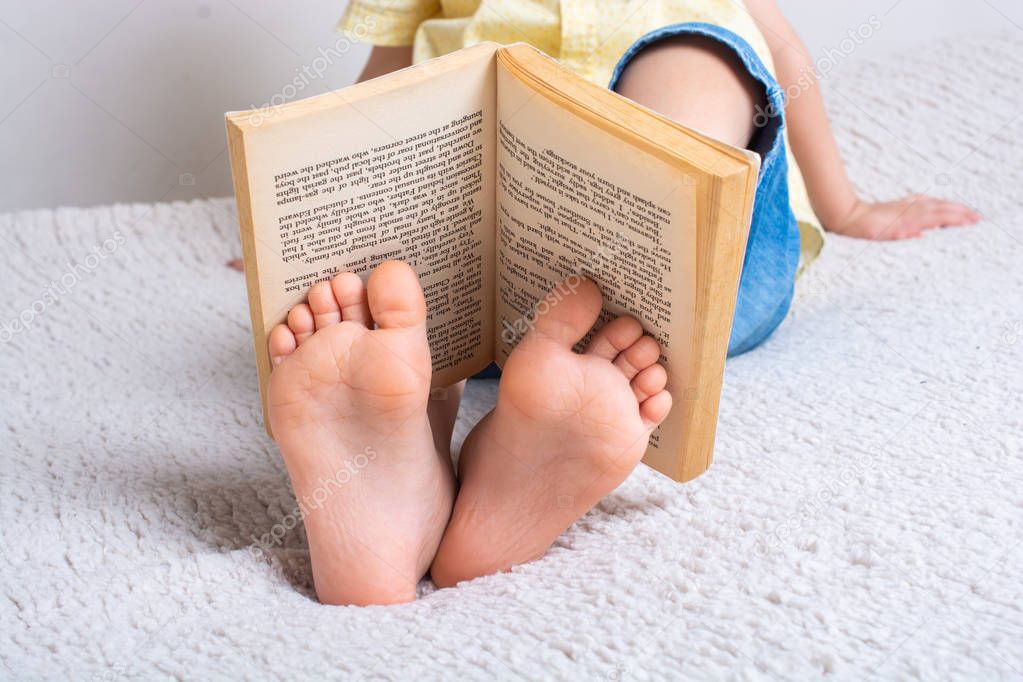 Boy holding book on feet as World book day concept