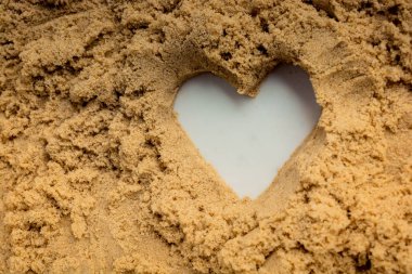 Heart shape made on the sand background clipart
