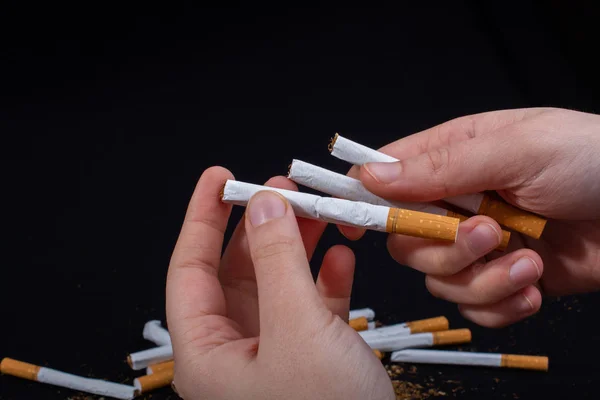 Mão está segurando cigarros no fundo preto — Fotografia de Stock